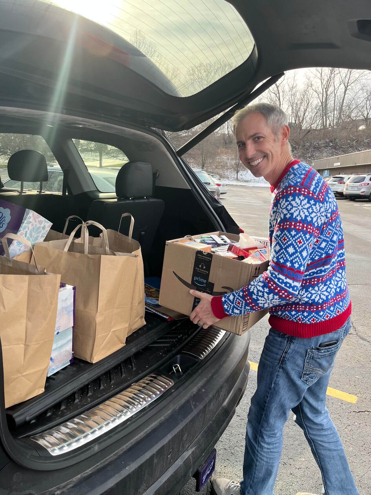 Smiling man loading boxes into the back of a car to take to the Open Door Mission