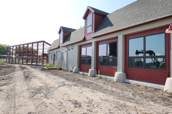 Renovation progress of a large, red commercial barn with construction site in view.