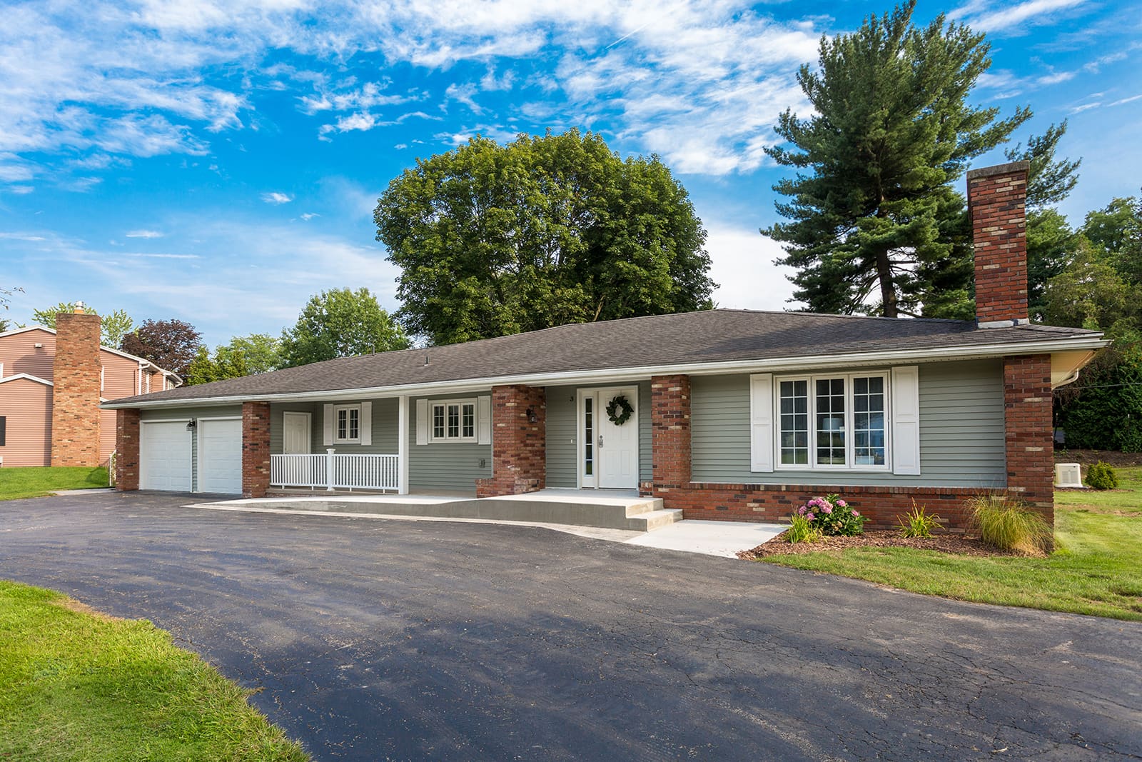 Single-story brick home with spacious driveway under blue skies, ideal for families.
