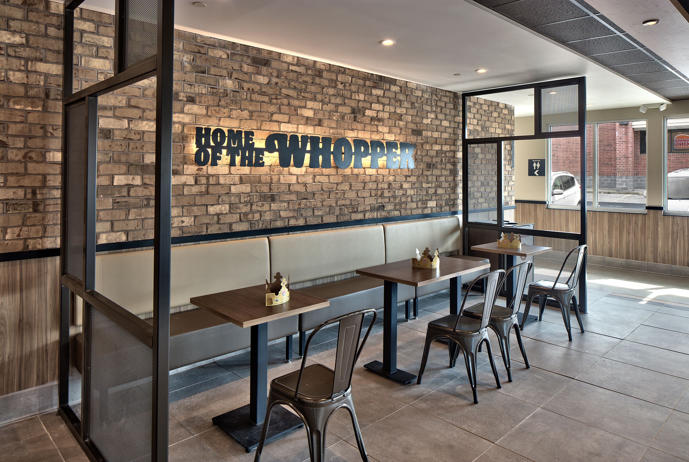 Modern Burger King interior with seating and Home of the Whopper sign on a brick wall.
