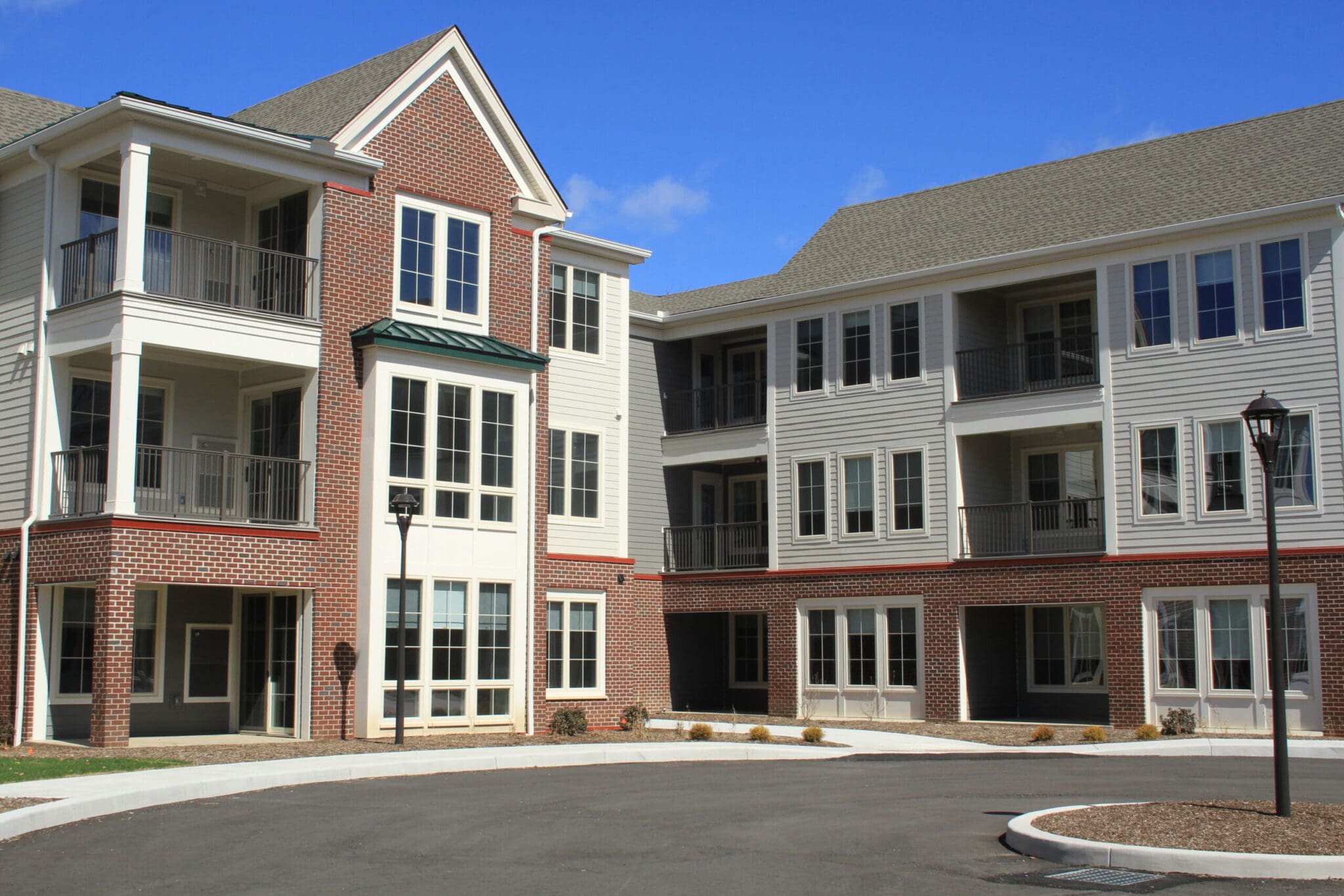 Modern apartment complex with brick and siding exterior under a clear blue sky. Perfect for urban living.