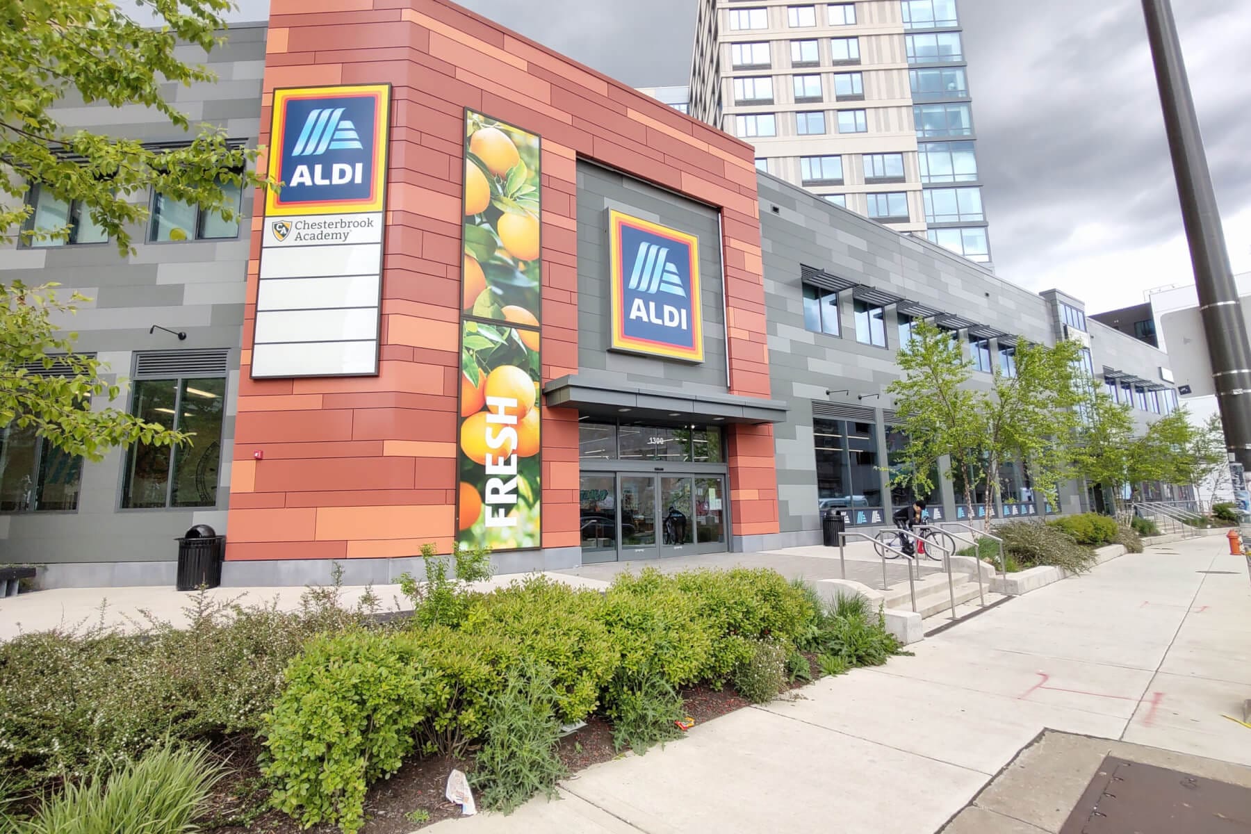 Modern ALDI store entrance highlighting fresh produce in urban setting, showcasing sustainable shopping options.
