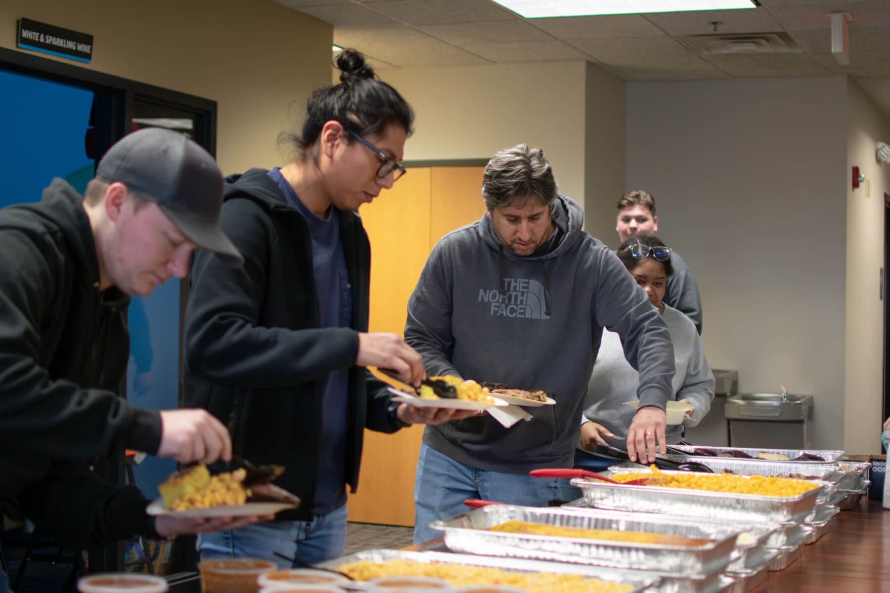People serving themselves at a buffet during a community event.
