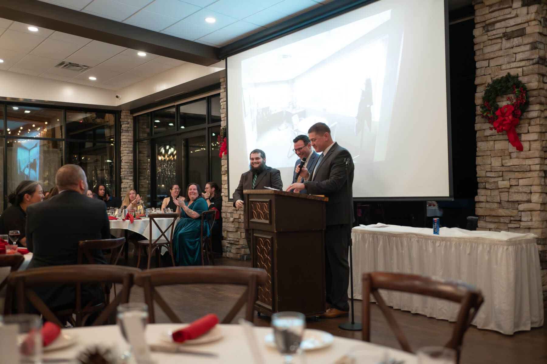 Speakers at a corporate event dinner. Attendees watch and listen attentively.