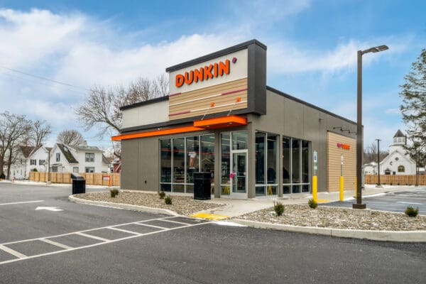 Modern Dunkin' store exterior with clear skies, showcasing brand's inviting design and accessible entrance.