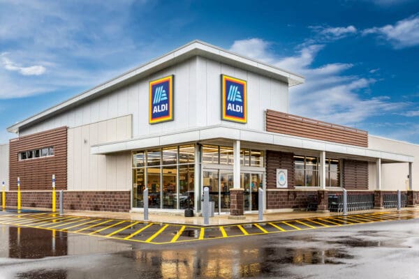Exterior view of an ALDI supermarket with clear blue sky, showcasing its modern design and welcoming entrance.