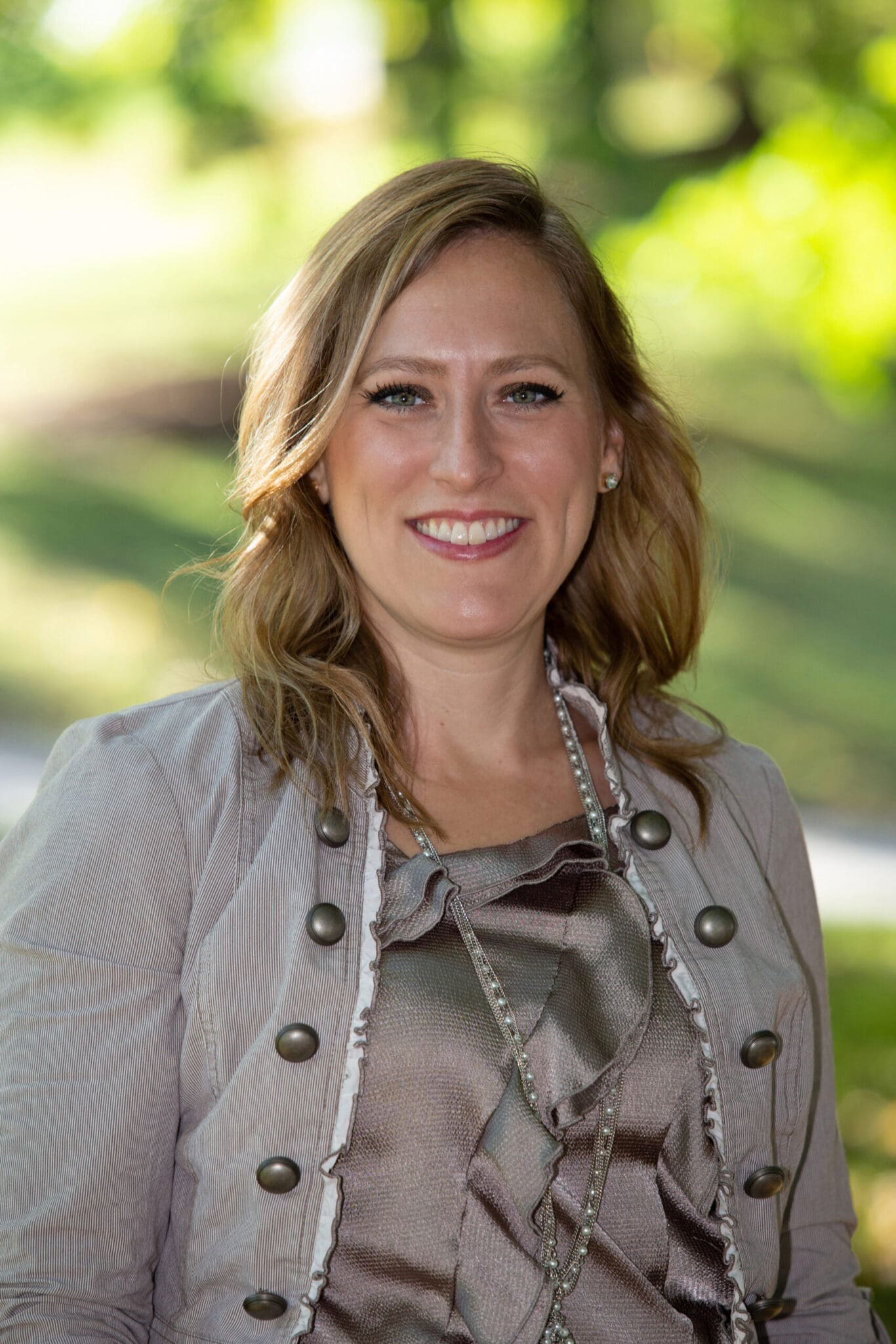 Smiling woman outdoors in stylish jacket, embodying confidence and elegance, suitable for professional networking.