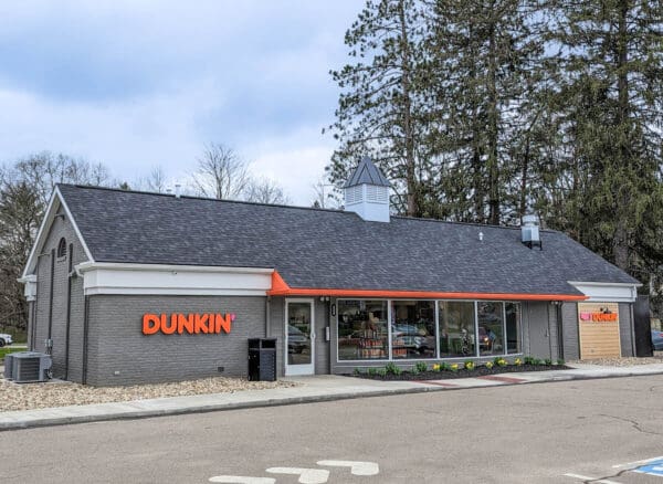 Exterior view of Dunkin' store with visible signage and modern design, set against a background of trees.