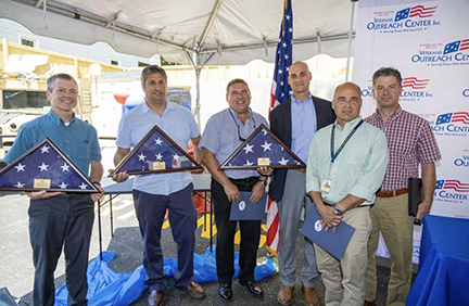 APD members holding up three folded American Flags at VOC Ribbon cutting ceremony