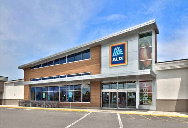 Aldi storefront with modern design and fresh produce signage under a clear blue sky.