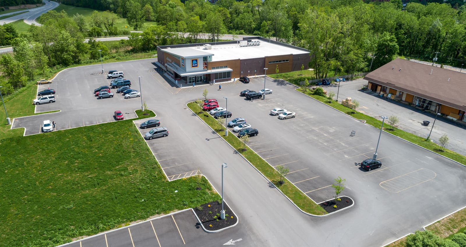Aerial view of a supermarket with a spacious parking lot surrounded by greenery.