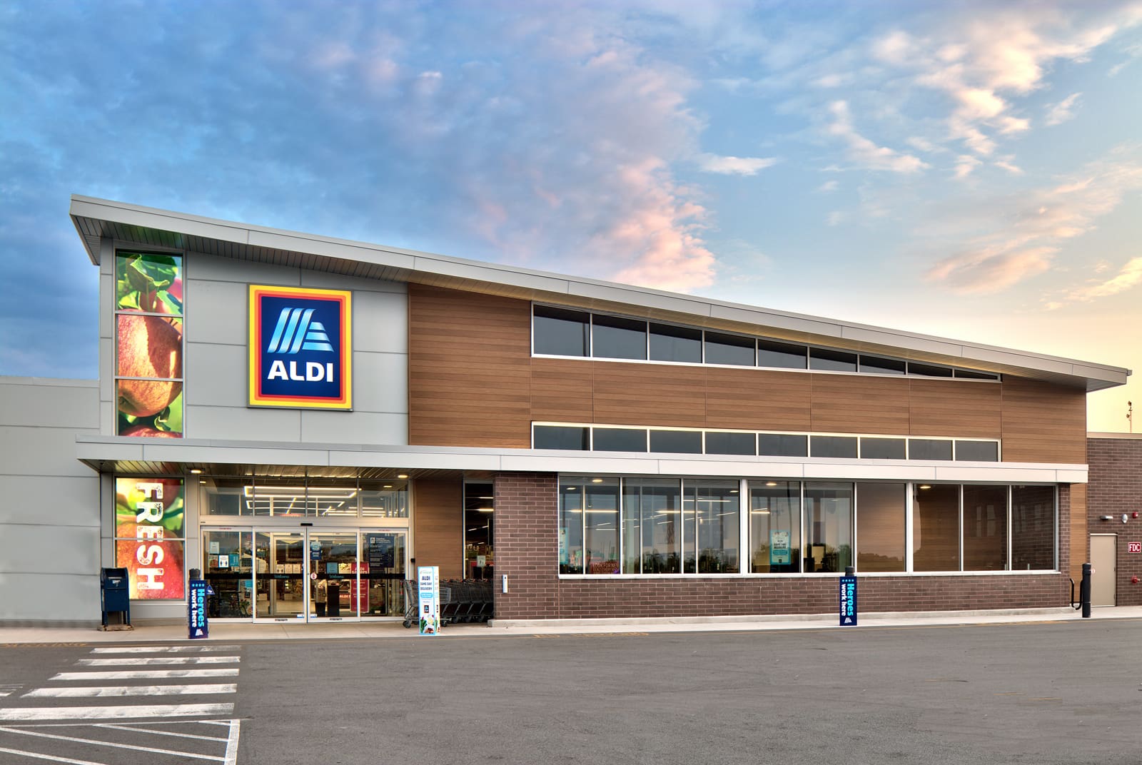 Exterior of an ALDI store under a blue sky, showcasing the modern design and welcoming entrance.