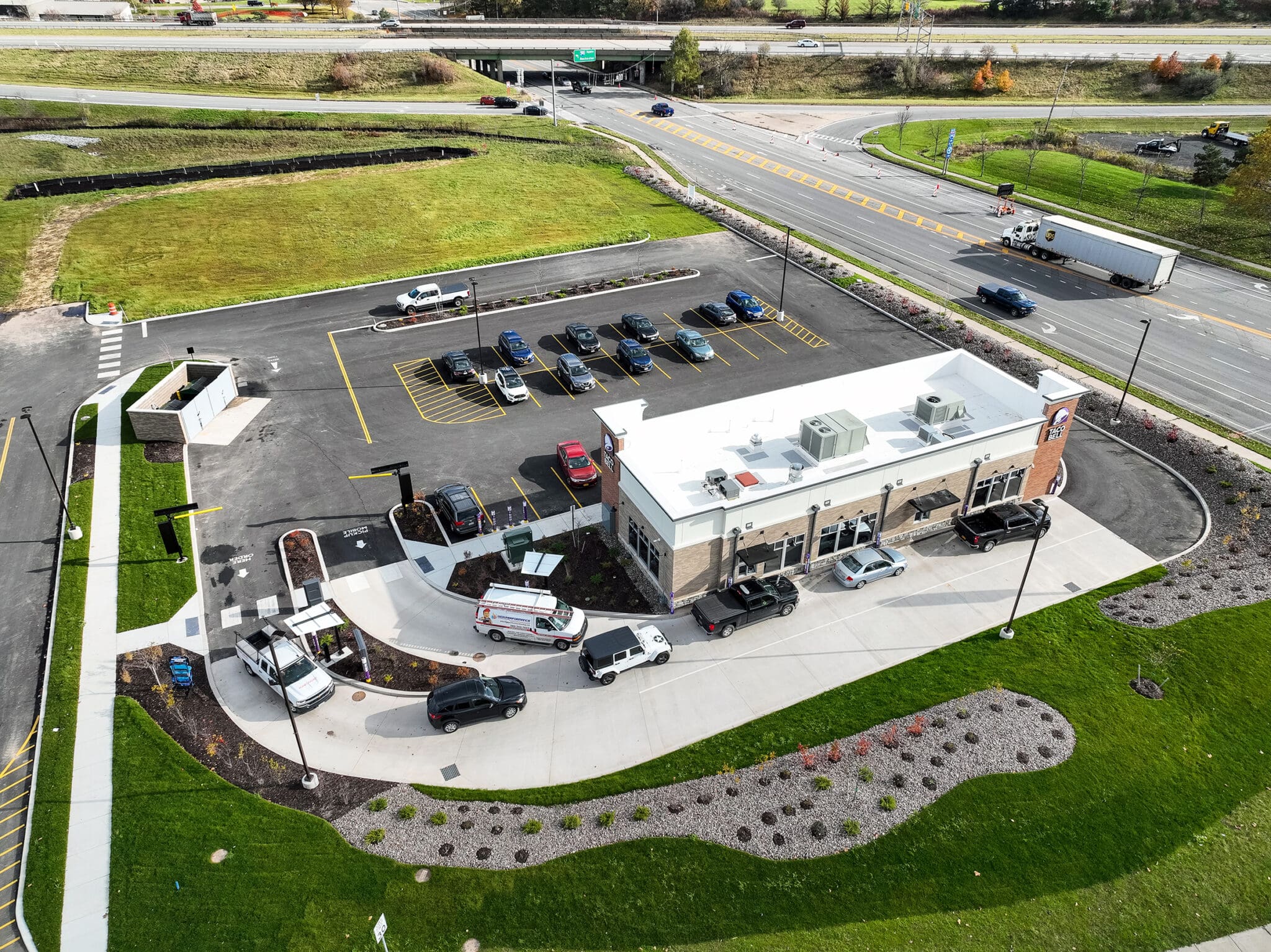 Aerial view of a drive-thru fast food restaurant and parking lot alongside a busy road.