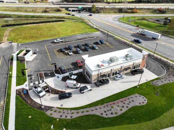 Aerial view of a drive-thru fast food restaurant and parking lot alongside a busy road.