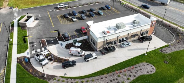 Aerial view of a drive-thru fast food restaurant and parking lot alongside a busy road.