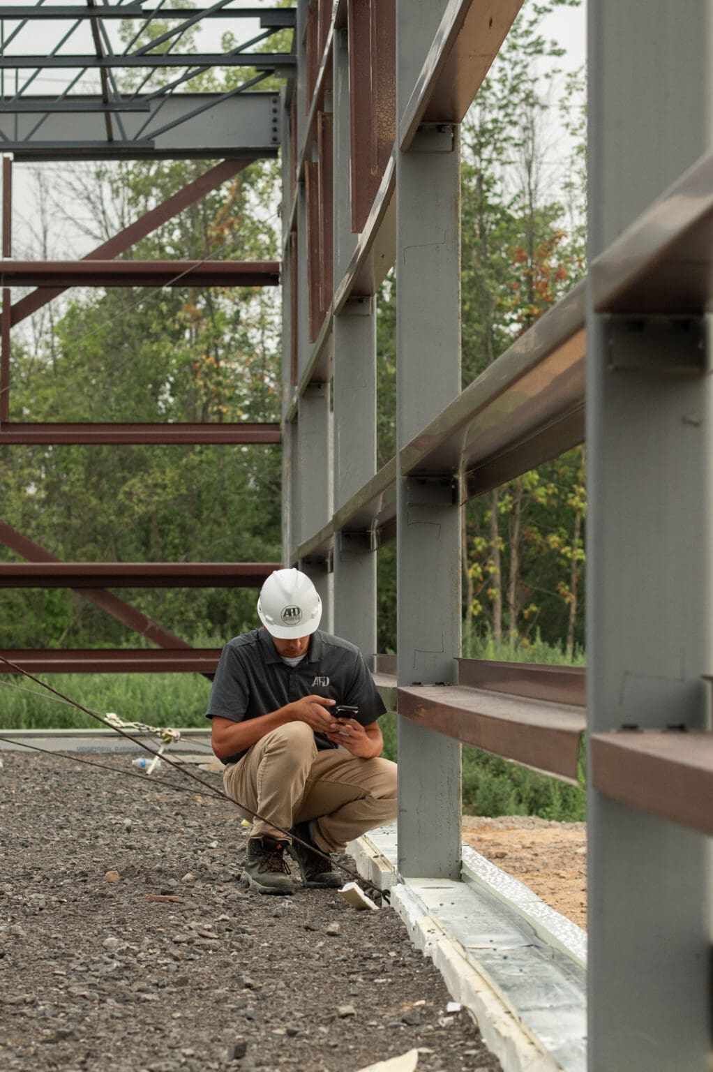 Construction worker checking plans at a metal building site.