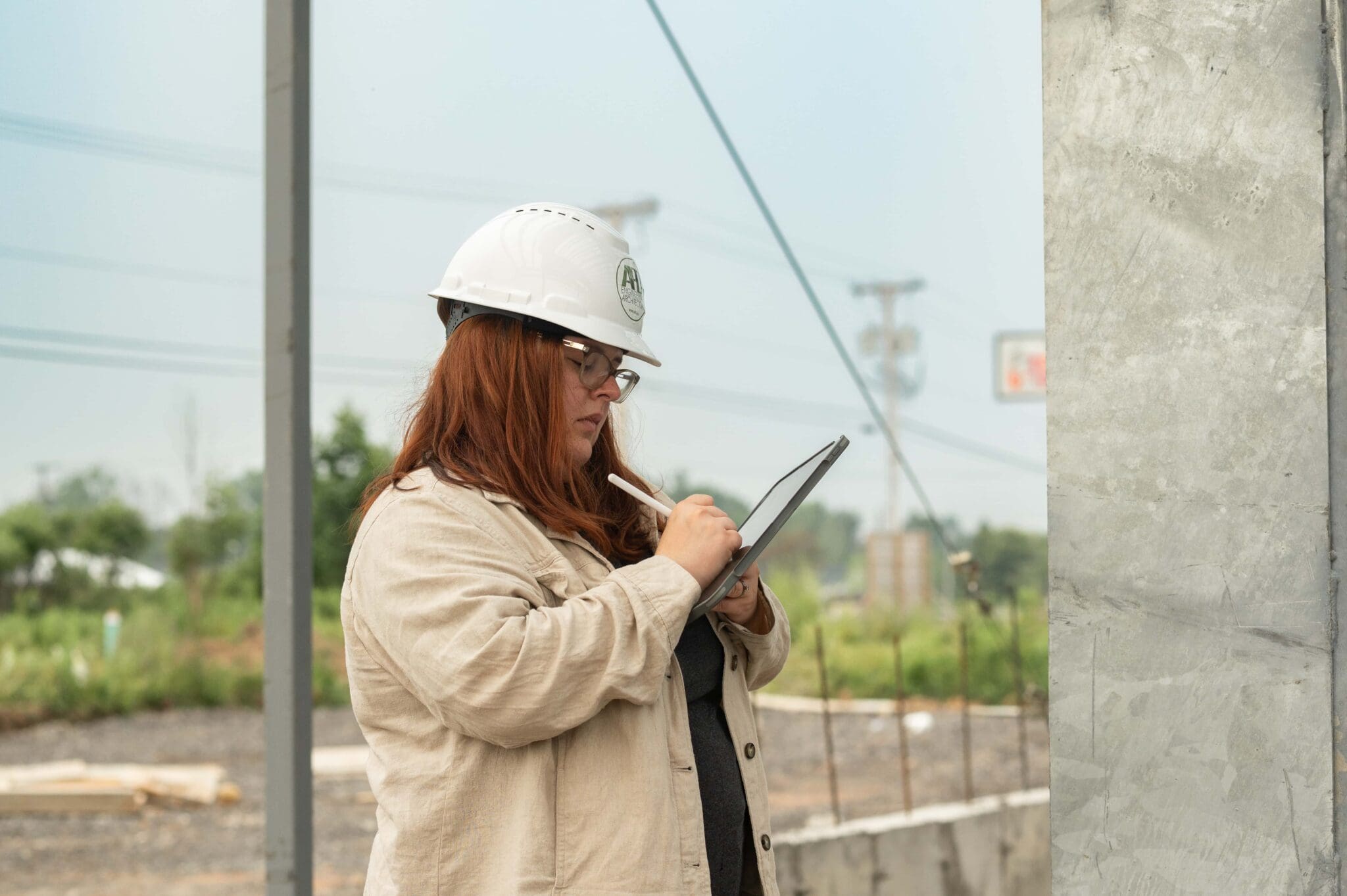 Construction manager reviews plans on tablet at building site.