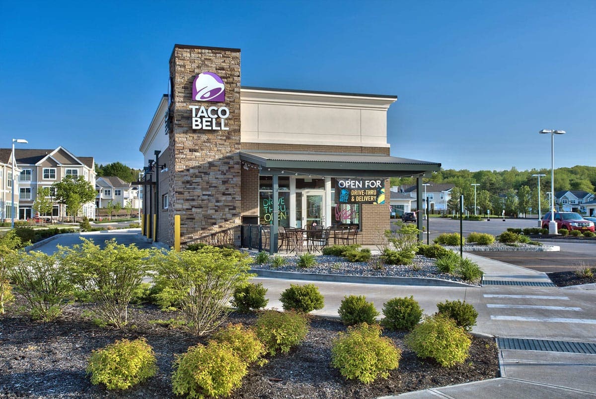 Taco Bell restaurant exterior showcasing drive-thru and delivery options.