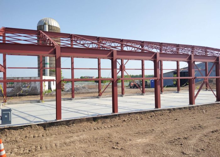 Steel frame construction for a new industrial building under clear skies.