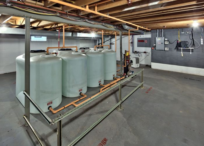 Commercial water storage tanks in a utility room setup, featuring extensive piping for efficient water management.