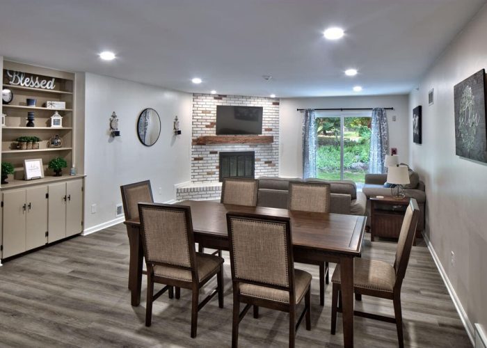 Cozy living room with dining table, brick fireplace, and garden view, perfect for family gatherings.