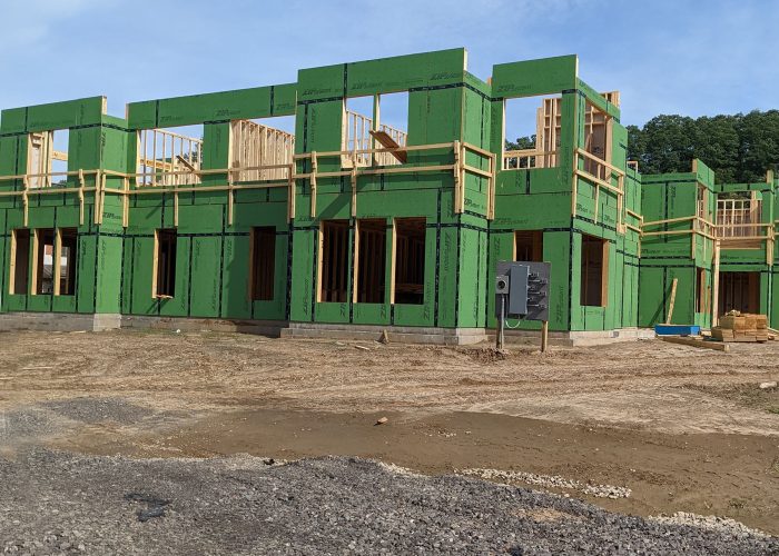 Construction site with green framed building under blue sky, showcasing modern architecture development.