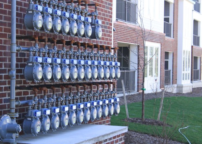 Row of gas meters on brick building exterior, demonstrating utility infrastructure efficiency.