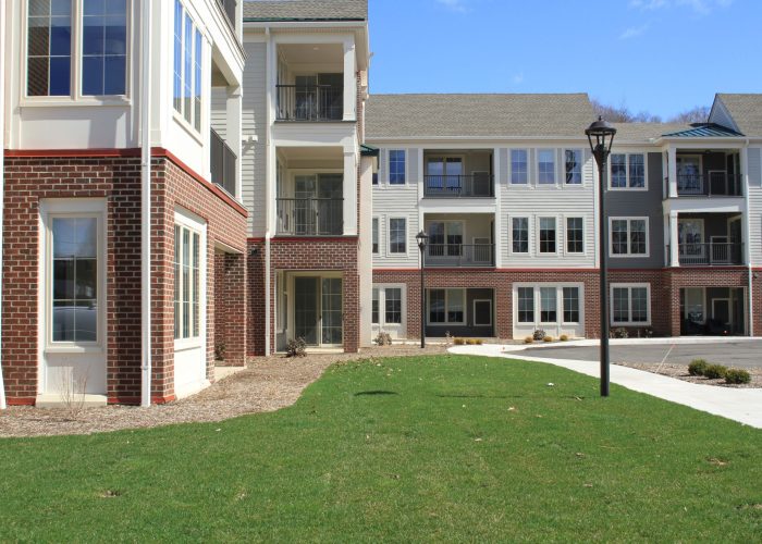 Modern apartment complex with brick facade and green lawn under a clear sky.