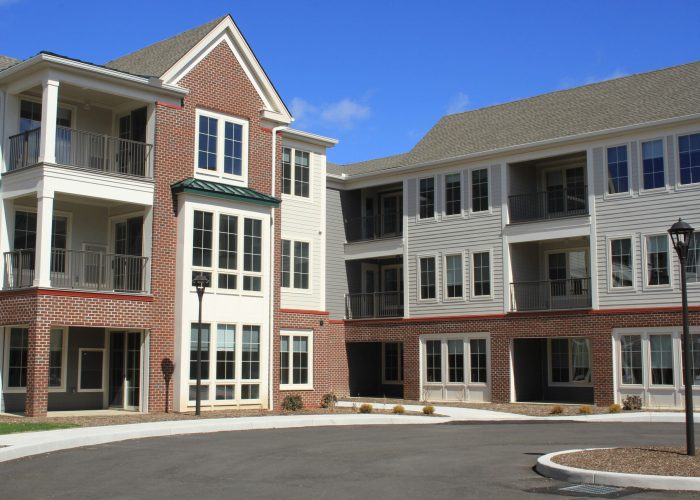 Modern apartment complex with brick and siding exterior under a clear blue sky. Perfect for urban living.