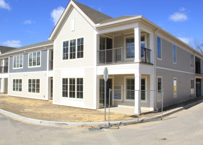 Newly constructed modern apartments with balconies under a clear blue sky, showcasing minimalist architecture.