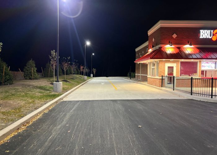 Night-lit drive-thru lane at fast food restaurant with bright exterior lights.