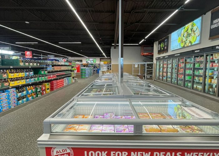 Aldi supermarket aisle featuring various grocery items and a weekly deals sign.