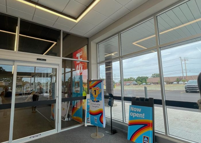 Bright entrance of newly opened Aldi store with signage highlighting low prices.