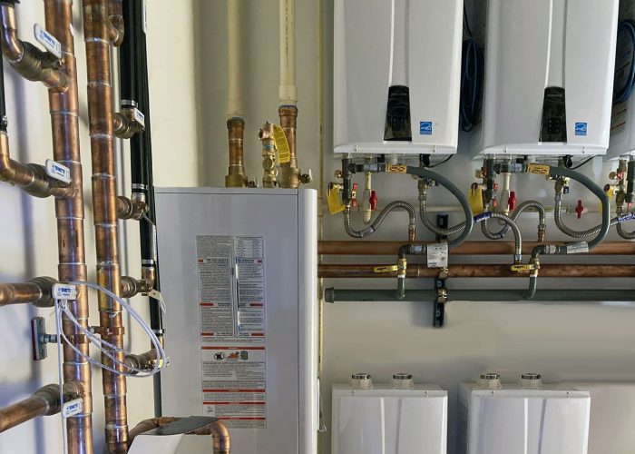 Tankless water heaters and copper piping system installed in a utility room for efficient home energy use.