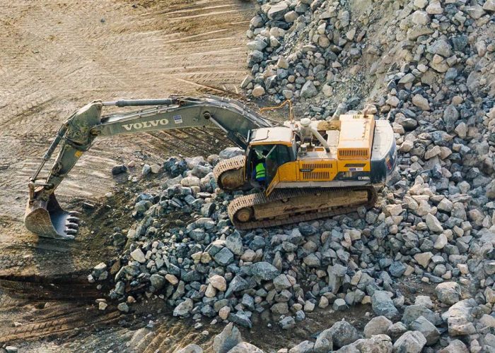 Excavator moving rocks in a quarry, demonstrating heavy-duty construction equipment in action.