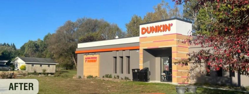 Renovated Dunkin' store exterior surrounded by trees and clear sky.