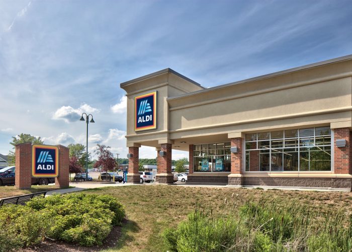 Exterior view of an Aldi store on a sunny day, showcasing its modern design and parking area.