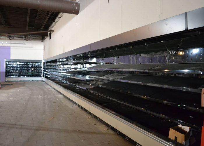 Empty supermarket shelves in a store under renovation, highlighting preparation for restocking.