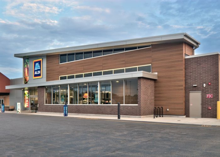 Exterior view of an Aldi store featuring modern design and clear branding against a cloudy sky.