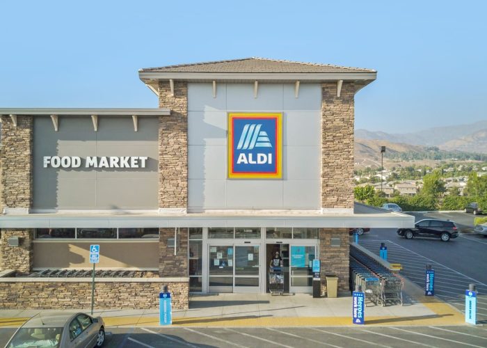 Exterior of ALDI food market with mountains in the background, highlighting store's welcoming entrance.