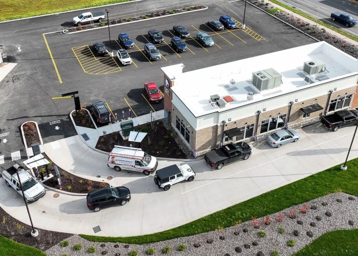 Aerial view of a drive-thru fast food restaurant and parking lot alongside a busy road.
