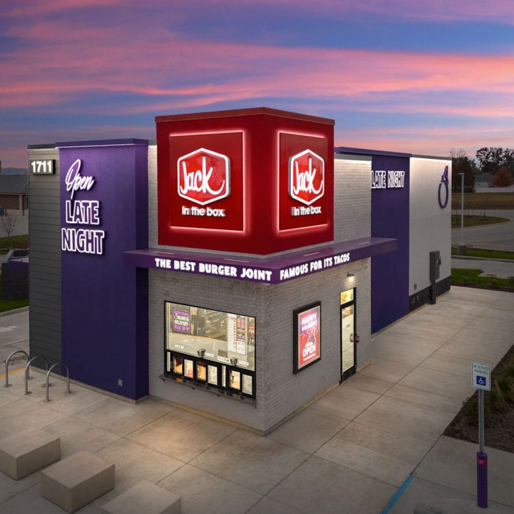 Jack in the Box restaurant illuminated at sunset, highlighting Open Late Night for burgers and tacos.
