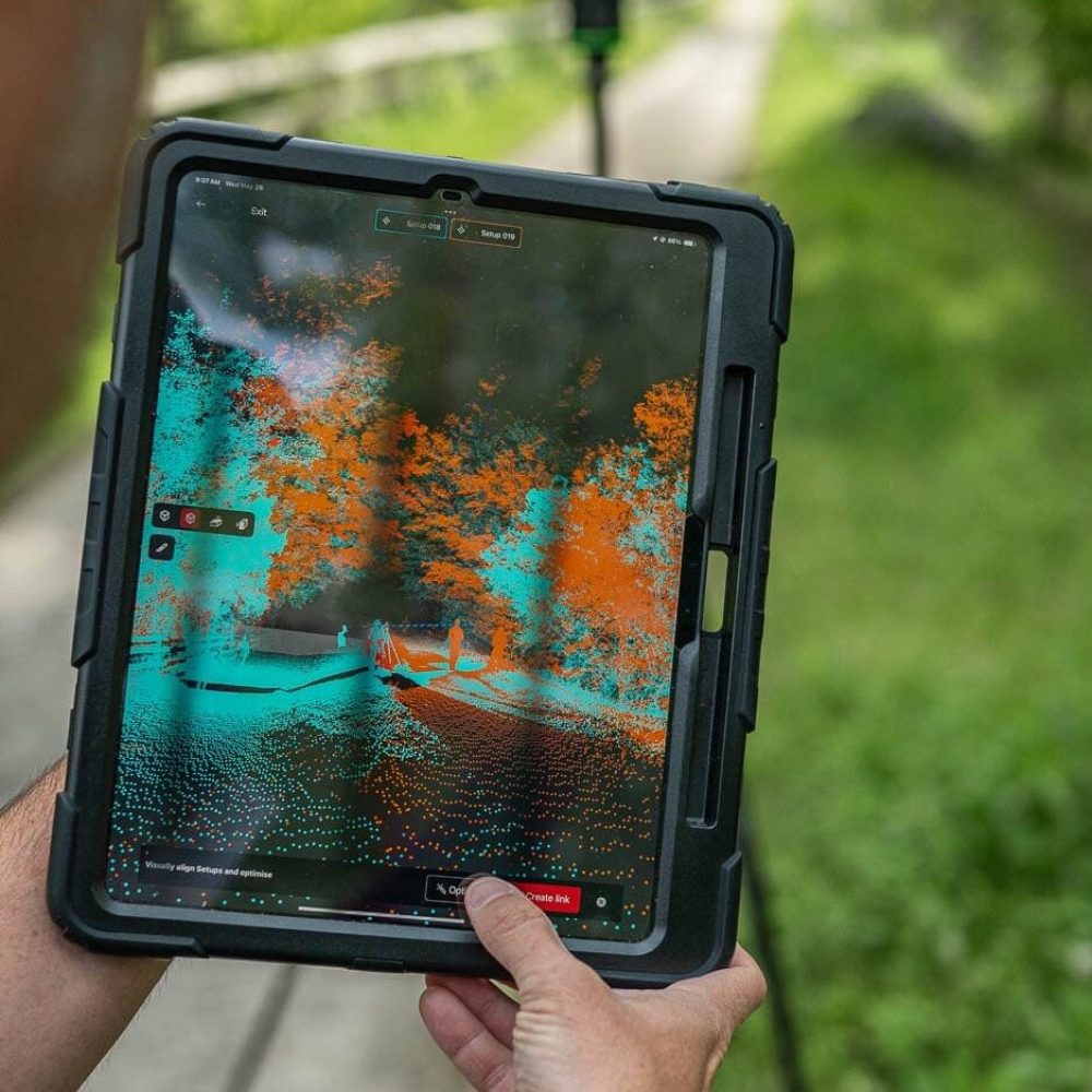 Person using tablet with LiDAR scanning on forest path.