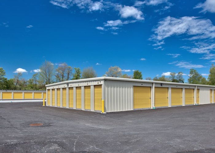 Outdoor self-storage units with yellow doors under a clear blue sky, ideal for secure storage solutions.