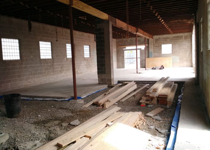 Construction site interior with materials and tools on a concrete floor, highlighting renovation progress.
