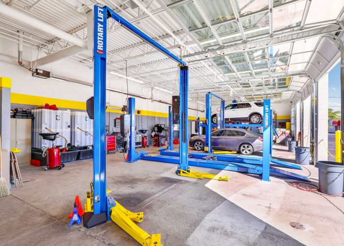 Auto repair shop with vehicles on lifts for maintenance. Bright, organized workshop showcasing advanced car repair equipment.