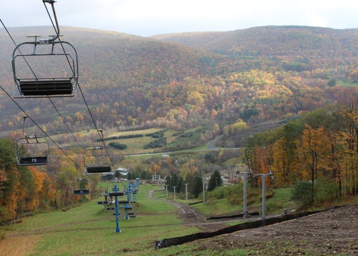 Scenic chairlift overlooking colorful autumn hills at a ski resort, showcasing vibrant fall foliage.