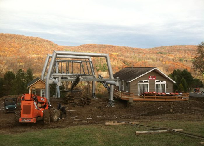 Construction of a ski lift near a patrol building during autumn at a mountain resort.