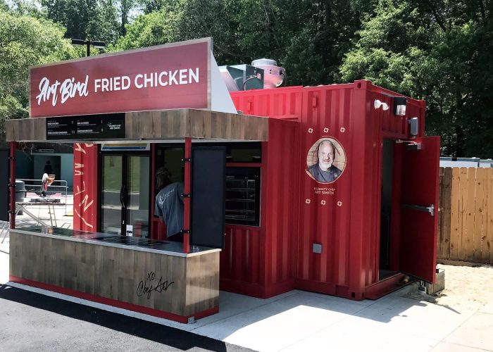 ArtBird's red fried chicken kiosk surrounded by trees, highlighting quick-service dining.