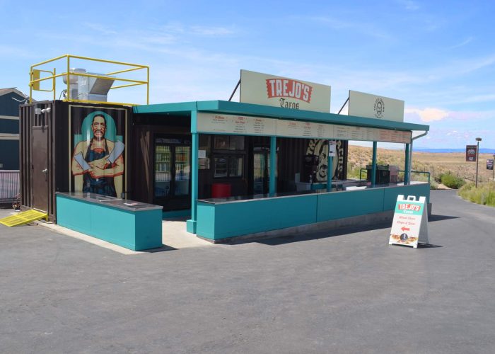 Trejo's Tacos stand with menu under clear skies, offering street food.